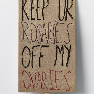 Kate Just, Keep Ur Rosaries Off My Ovaries, 2022, knitted wool as placard with plywood stand, 90 x 52 cm