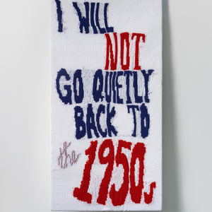 Kate Just, I Will Not Go Quietly Back to the 1950s, 2022, knitted wool as placard with plywood stand, 112 x 57 cm