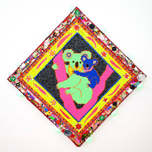 Koalas (Green & Blue), 2025, acrylic yarn needlepoint embroidery on canvas, felt, fabric, ribbon, cotton thread, laminated leaves, plastic teddy bear eyes, tassels, trim, buttons, beads, sequins, glitter, glass, shells, found objects, eyelets, LED light, wood, adhesive, fixtures, and enamel, 91.5 x 91.5 x 5 cm
