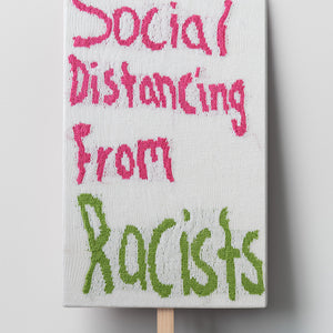 Kate Just, Social Distancing From Racists, 2022, knitted wool as placard with plywood stand, 76 x 46 cm